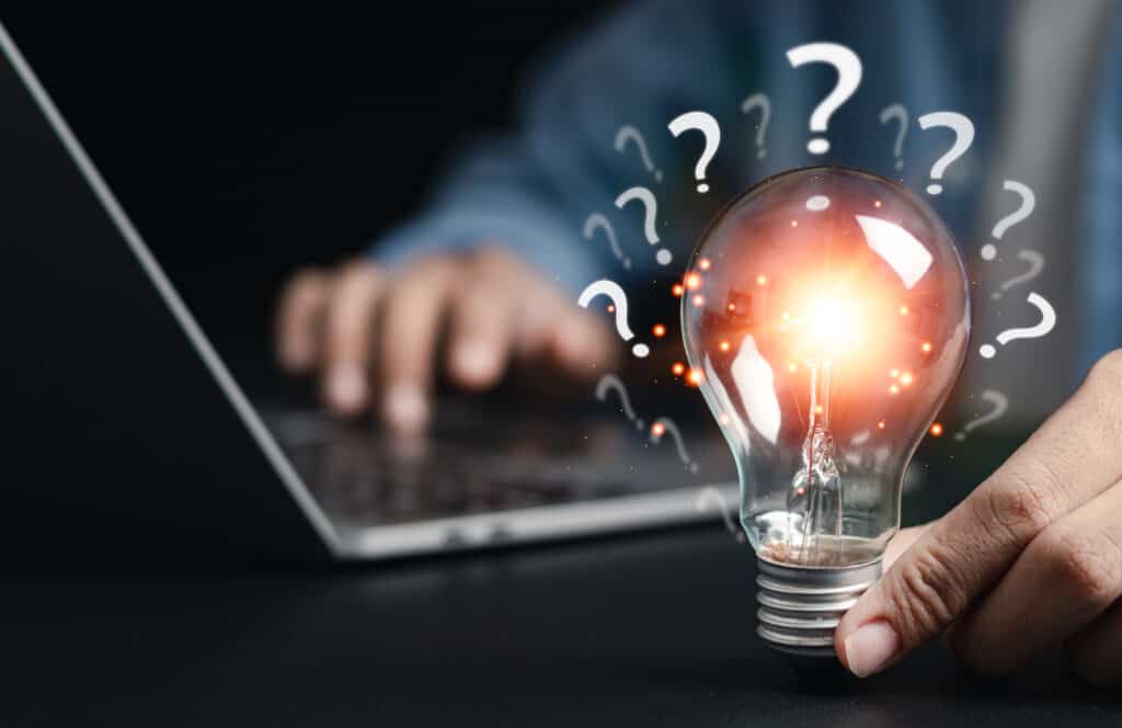 Businessman holding glowing light bulb with question icon. Find answers online. FAQ search for information on the internet