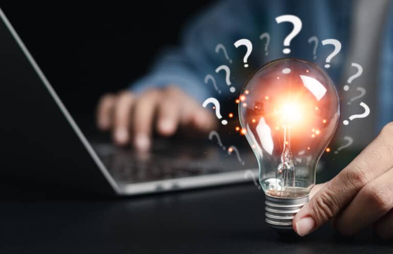 Businessman holding glowing light bulb with question icon. Find answers online. FAQ search for information on the internet